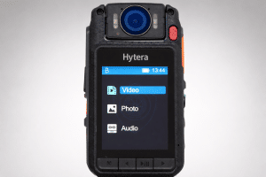 Rugged Hytera handheld radio displaying a menu: Video, Photo, Audio on the screen. Visual focus on the device's front panel and lens above the screen.